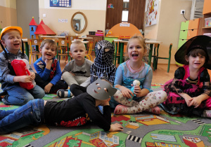 Dzieci przebrane za postacie z bajek, siedzą na dywanie.